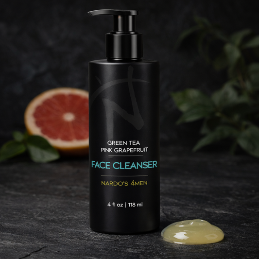 Black face cleanser bottle labeled 'Green Tea Pink Grapefruit' on a dark surface with a half-cut grapefruit and green leaves in the background.