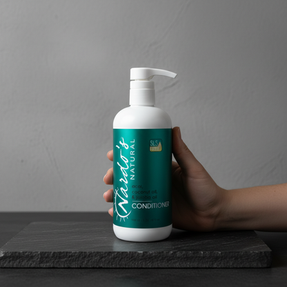 Hand holding a bottle of 'Nado's Natural' conditioner against a gray background